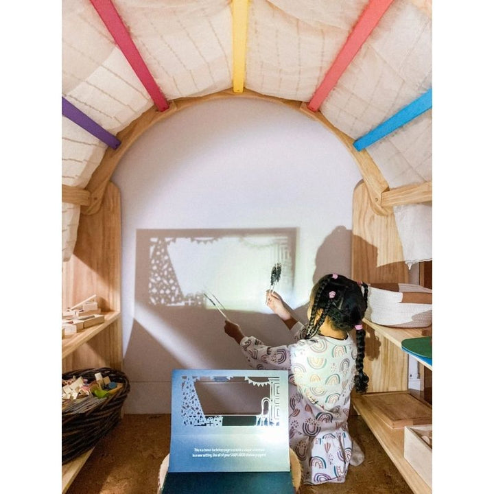 Child engaged in shadow play with the Kinderhuis Aurora Waldorf Playstand, demonstrating creative sensory play in a home environment