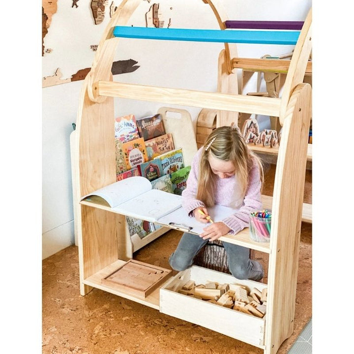 Child using the Kinderhuis Aurora Waldorf Playstand as a writing and reading nook, illustrating versatile Montessori play furniture use