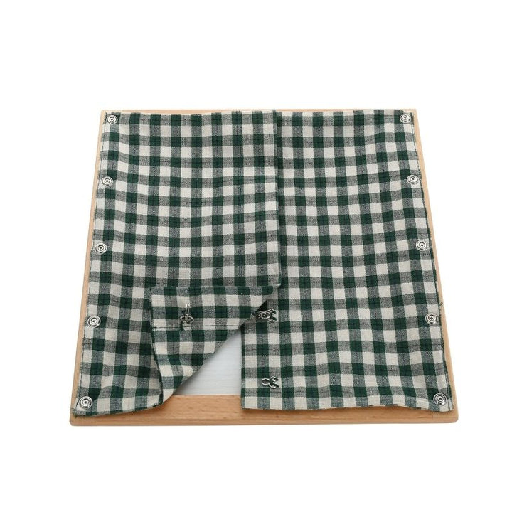 Kinderhuis Montessori dressing frame with green check textile panel, AMI-approved practical life material for children