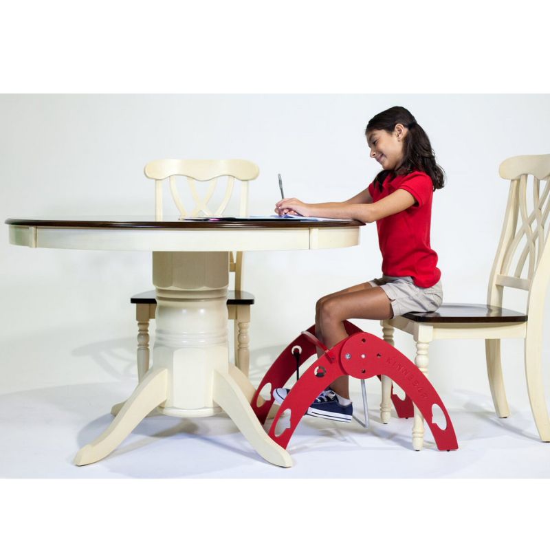 Side view of a girl using the Kinnebar K200 Foot Swing at a desk while studying, showing in-seat movement and sensory input during a learning task