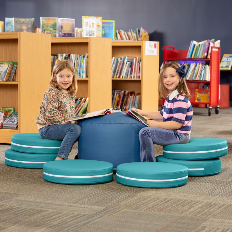 Two children reading in a library while seated on Jaxx Kirkwood teal stacking floor cushions around a blue ottoman
