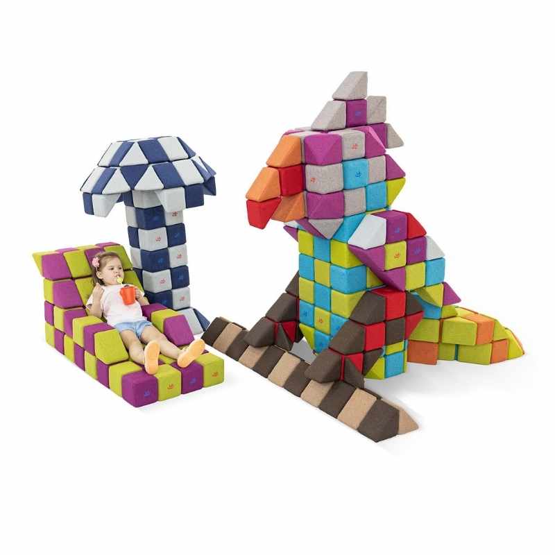 A child relaxes on a lounge chair beside a cockatoo and palm tree structure built from JollyHeap Fun Set magnetic building blocks