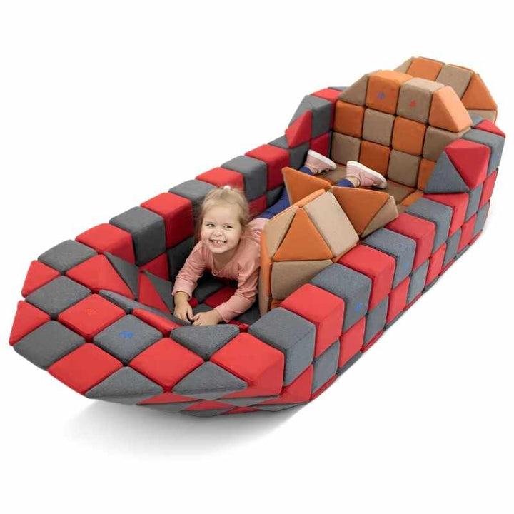 A child plays inside a large boat structure built from the JollyHeap Fun Set magnetic building blocks in red, grey, orange and tan