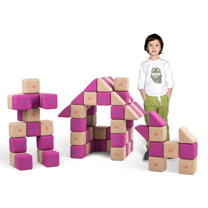 A child stands beside a house structure and robot figure built from the JollyHeap Fun Set large group magnetic building blocks