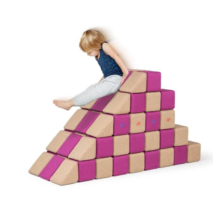 A child climbs a pyramid shaped staircase structure built from the JollyHeap Fun Set magnetic building blocks in magenta and tan