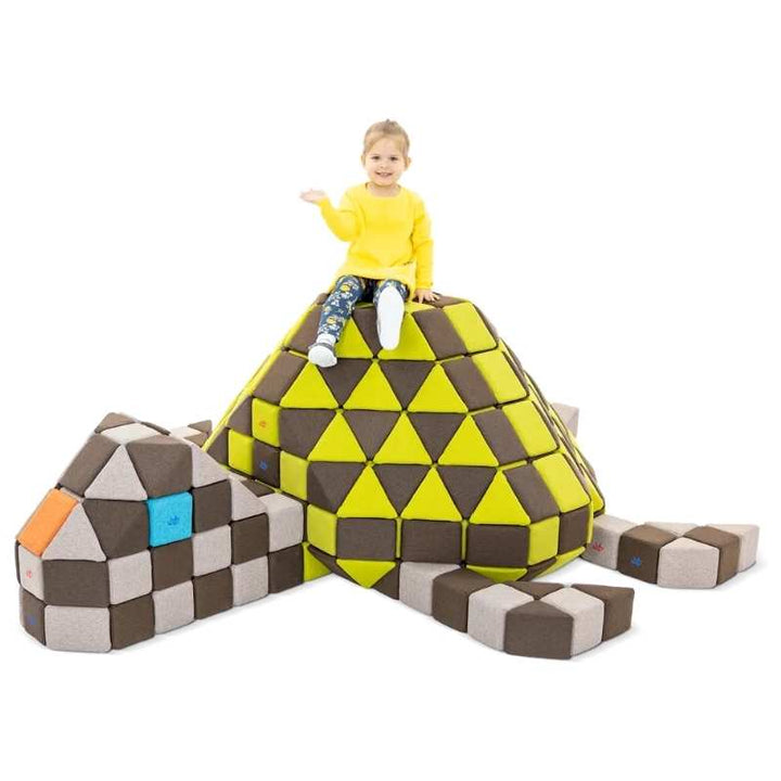 Child sitting on a turtle structure built from the JollyHeap large magnetic foam block set