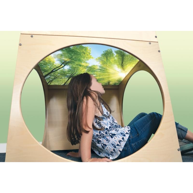 Girl resting inside the Whitney Brothers Superbright LED Creative Cube, gazing up at the sunlit forest canopy printed under the top of this light table reading cube and quiet space