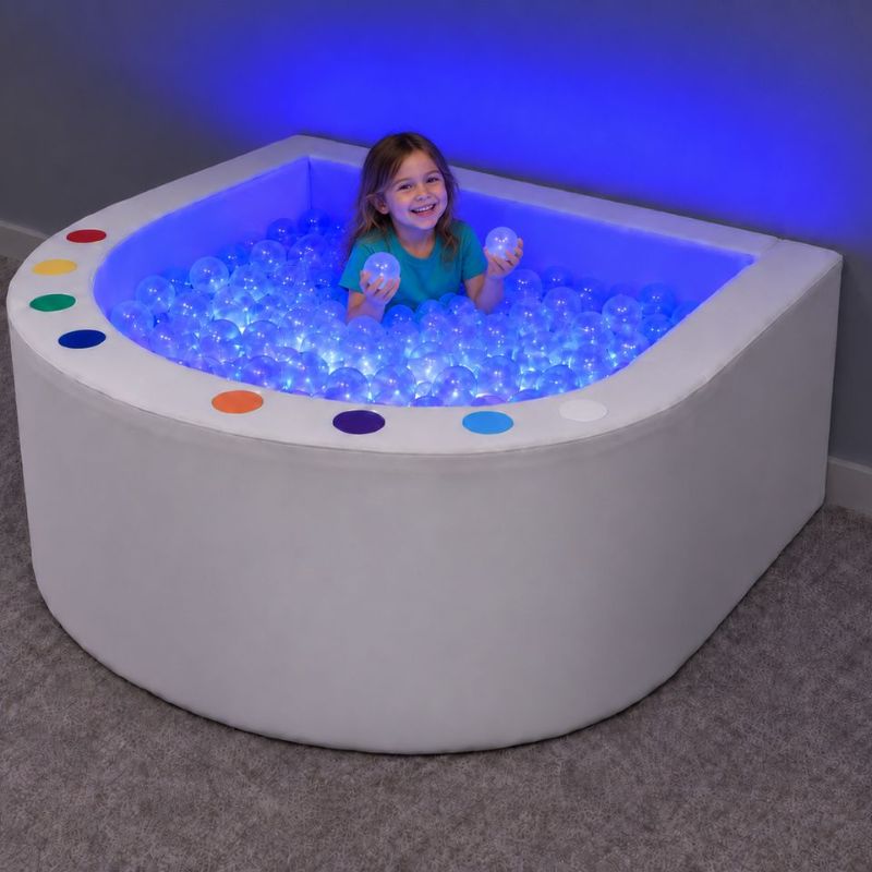 Child playing in the curved Experia Interactive LED Ball Pool, a light up ball pit that brings color and calm to sensory rooms and home play spaces