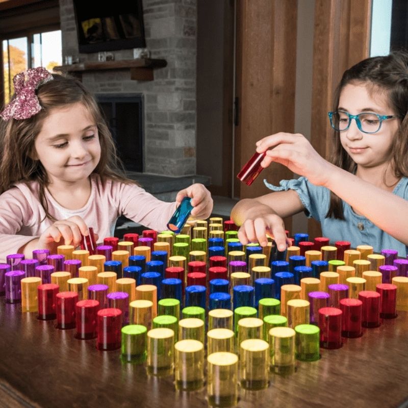 Two children placing colourful LitePins on the LiteZilla Mini interactive light board during active sensory play