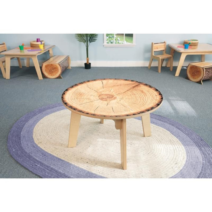 Whitney Brothers Nature View Live Edge Activity Table in round shape with a cross-cut tree ring top, a nature-inspired preschool table on a classroom rug