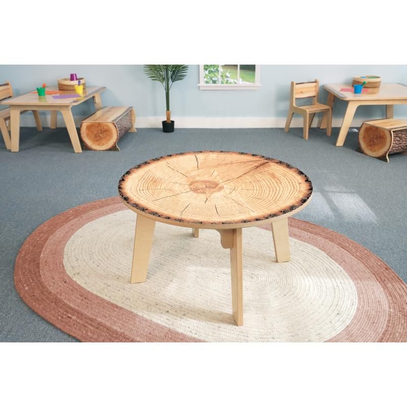Whitney Brothers Nature View Live Edge Round Table 18H on a round woven rug, a biophilic kids activity table with realistic tree rings in a bright early learning classroom