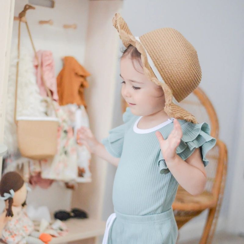 Child actively using the Sapiens Child Mango Montessori Cubby Coat Rack, showing the child-sized entryway organiser with seat, 6 hooks, and boot storage made in Vancouver Canada