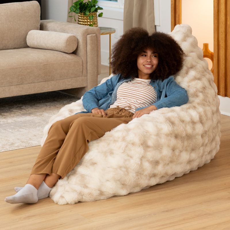 Teen reclining in the Raven-Symoné LoungePuff micro-cushion faux fur lounger in Phantom Cream