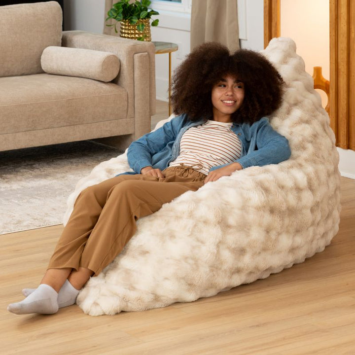 Teen reclining in the Raven-Symoné LoungePuff micro-cushion faux fur lounger in Phantom Cream