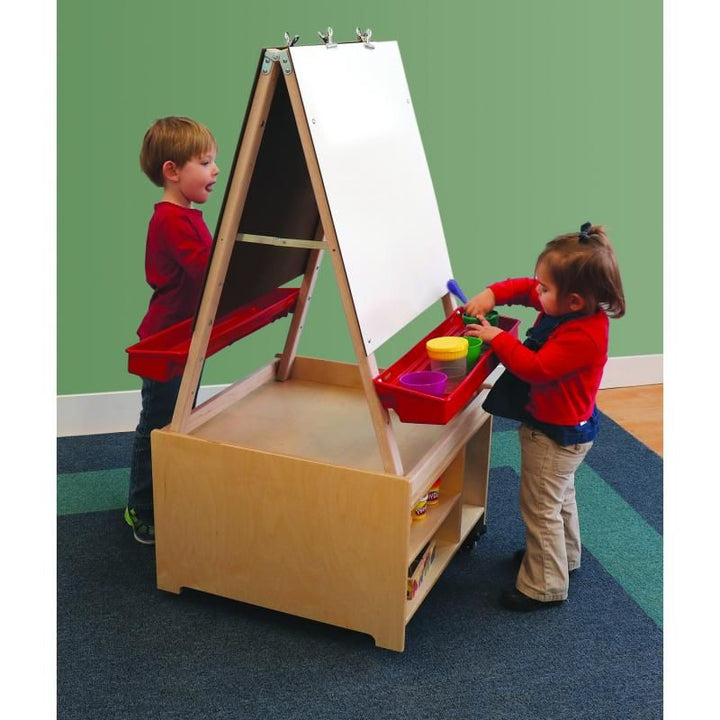 Two young children using the Whitney Brothers Mobile Art Center Two Station Set together, sharing a double-sided kids art easel with paint cups in the adjustable paint tray