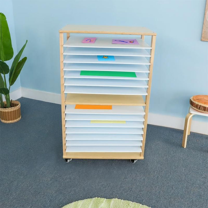 Whitney Brothers Mobile Art Drying Rack holding colorful children's artwork in a bright playroom, a classroom art drying rack that works just as well at home