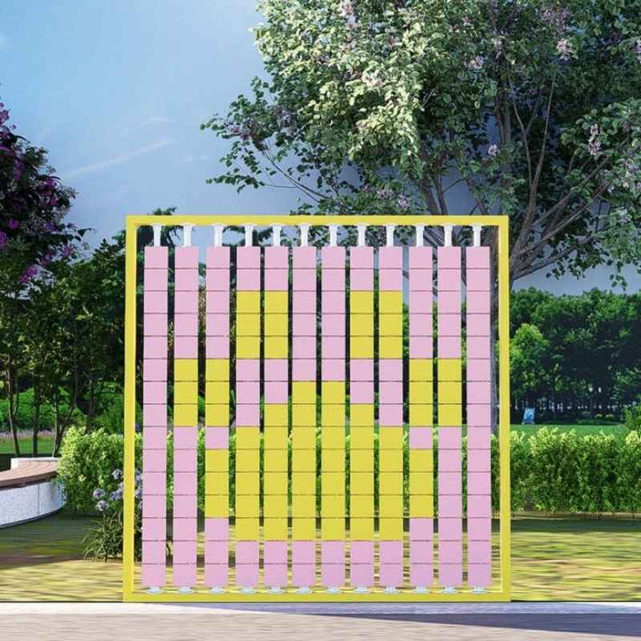 LiteZilla Mosaico Wall interactive STEM wall panel installed outdoors in a garden setting with pink and yellow rotating tiles