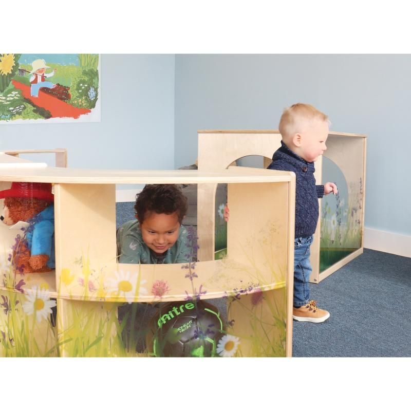 Smiling child stands behind the clear acrylic nature scene of a Whitney Brothers Nature View Curve Cabinet used as a daycare room divider