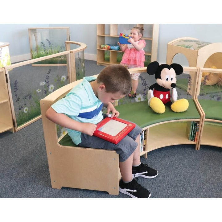 Boy drawing on a Whitney Brothers Nature View Curved Sofa, part of a biophilic classroom furniture reading area