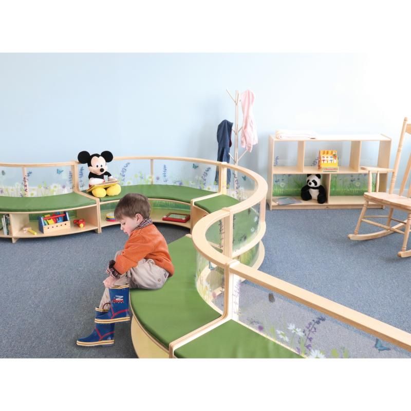 Toddler pulling on boots while seated on Whitney Brothers Nature View Curved Sofas arranged in a winding classroom layout