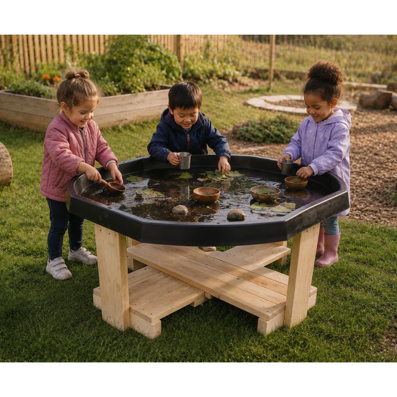Three children playing at the ONP Active World Tray Stand in a garden, scooping water with cups and floating leaves and bowls on the wooden stand