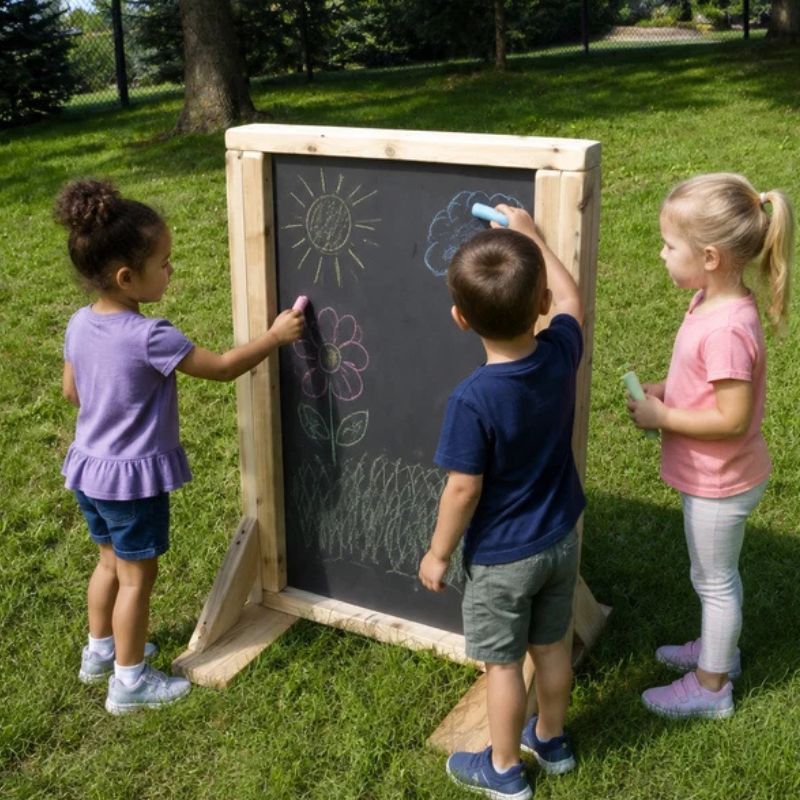 Three children drawing with chalk on the ONP Double-Sided Infant Art Easel outdoors, creating sun, flower and cloud designs on the chalkboard surface