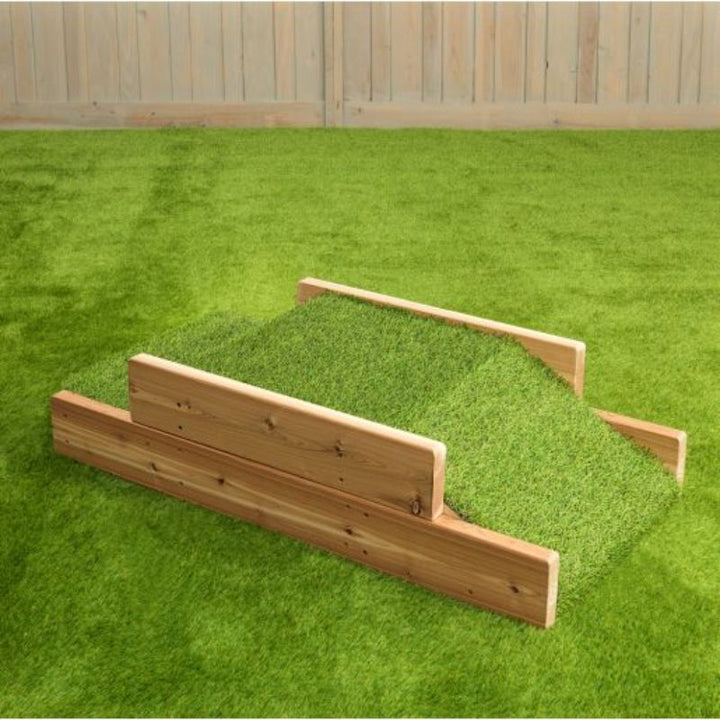 ONP Infant Step and Ramp side view showing the Western Red Cedar frame, faux grass ramp surface, and 2-step reverse side of this outdoor infant crawl and climb structure for gross motor development in early years settings across Canada and the US