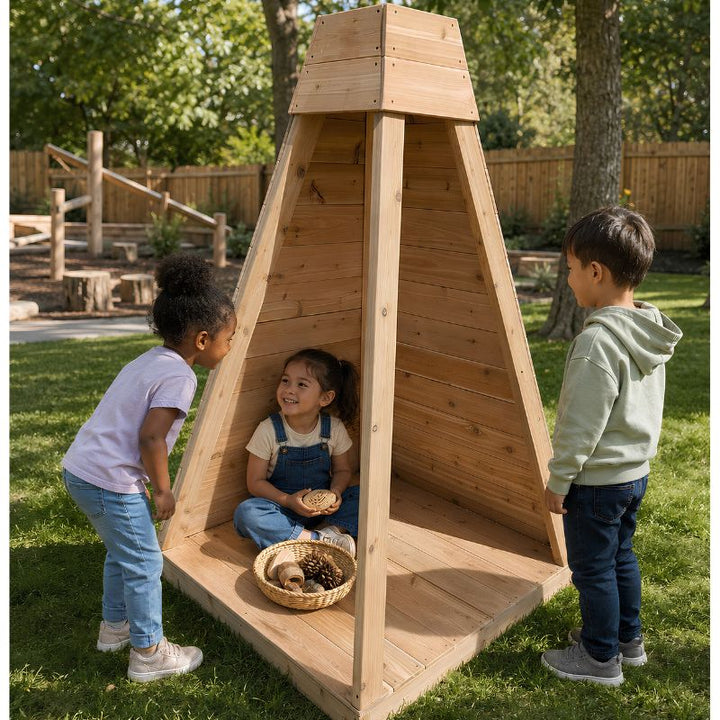 A girl sitting inside the pyramid-shaped ONP Outdoor Reading Nook outdoors, with two children looking in and a basket of pinecones nearby