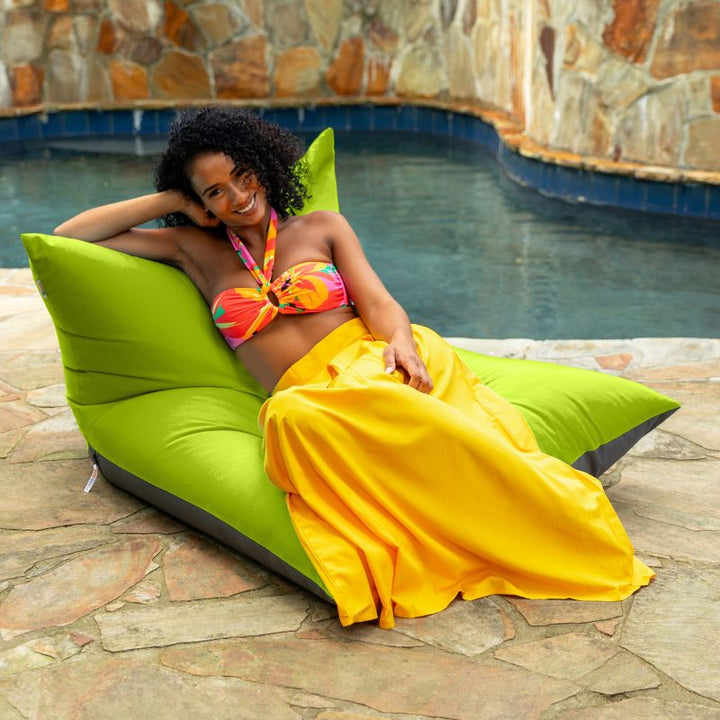 Woman lounging on the Jaxx Finster outdoor bean bag chair in Lime Sunbrella fabric