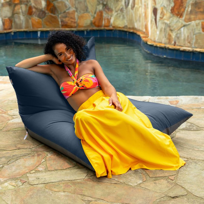 Woman lounging on the Jaxx Finster outdoor bean bag chair in Navy Sunbrella fabric