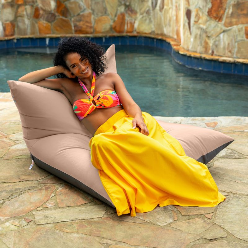 Woman lounging on the Jaxx Finster outdoor bean bag chair in Petal Sunbrella fabric