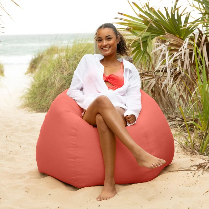 Woman relaxing in a Flamingo Jaxx Kiss outdoor bean bag chair among beach dunes