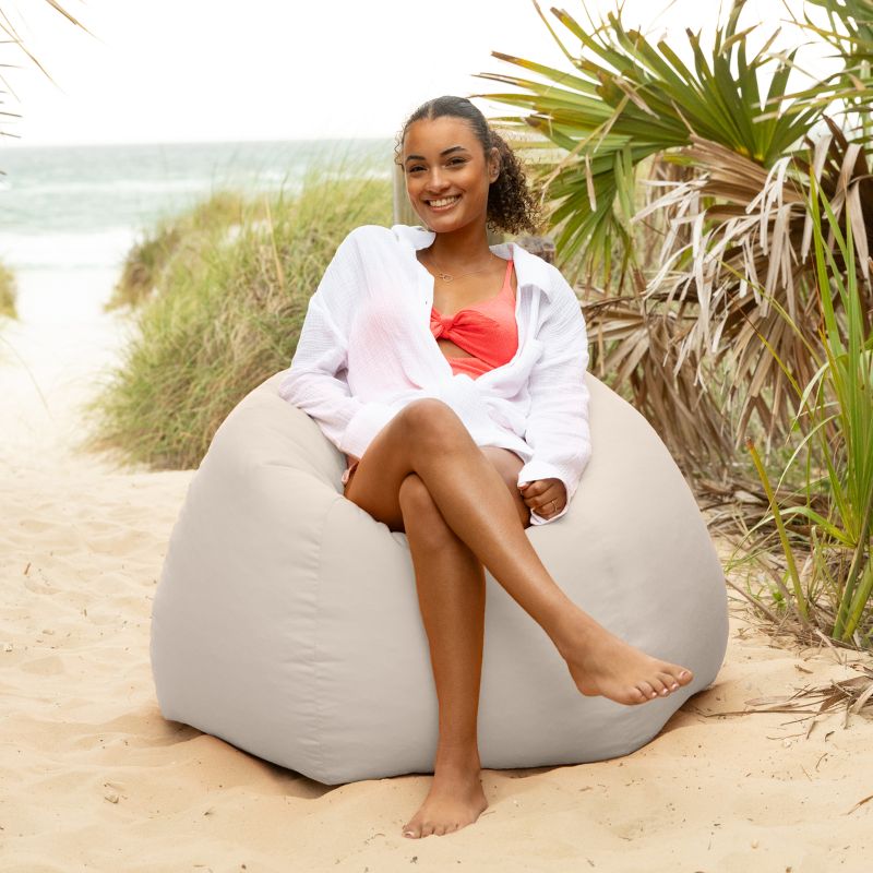 Woman relaxing in a Pearl Jaxx Kiss outdoor bean bag chair near beach dunes