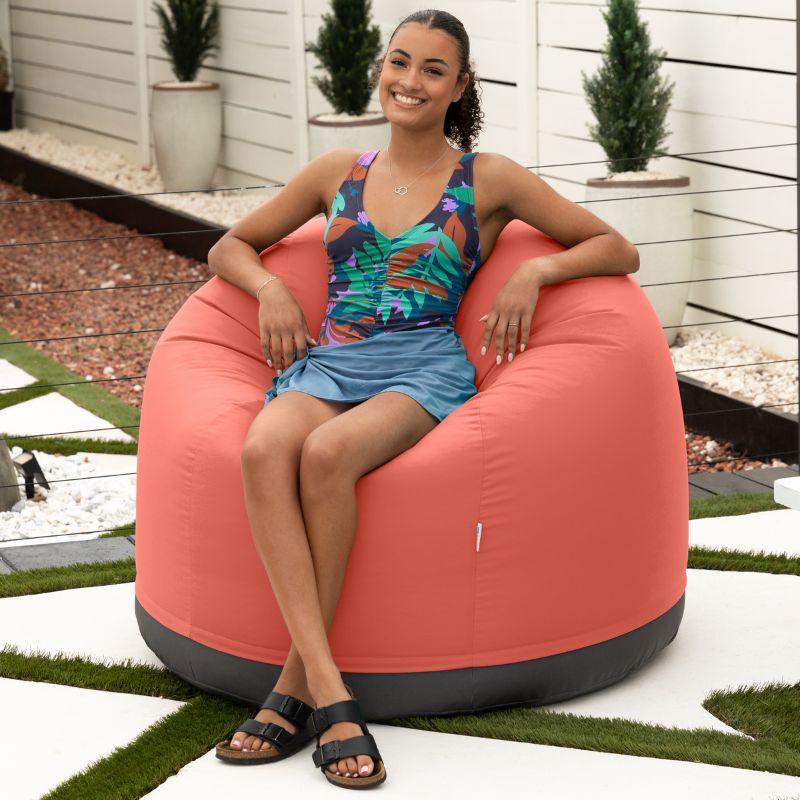 Woman relaxing outdoors in the Jaxx Palmetto outdoor bean bag chair in Flamingo Sunbrella fabric