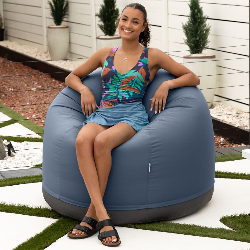 Woman relaxing on a beach in the Jaxx Palmetto outdoor bean bag chair in Navy Sunbrella fabric