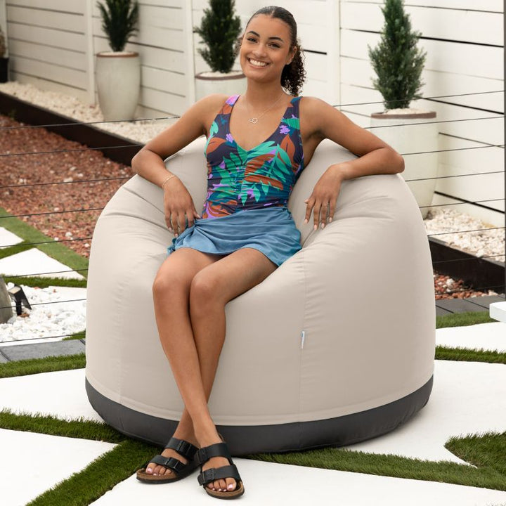 Woman relaxing on a beach in the Jaxx Palmetto outdoor bean bag chair in Pearl  Sunbrella fabric