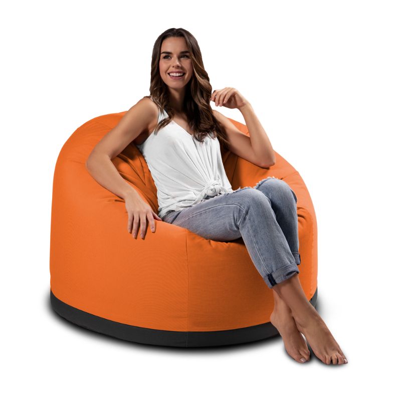 Woman relaxing outdoors in the Jaxx Palmetto outdoor bean bag chair in Tangerine Sunbrella fabric