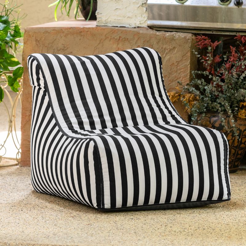 Jaxx Ponce Outdoor Bean Bag Chair in Black & White Stripes on a patio beside potted plants, a striped poolside bean bag for cozy outdoor corners
