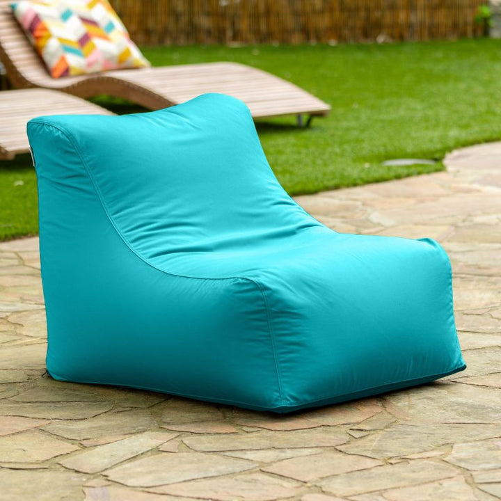 Jaxx Ponce Outdoor Bean Bag Chair in Lagoon on a stone pool deck, a turquoise boat and poolside bean bag chair