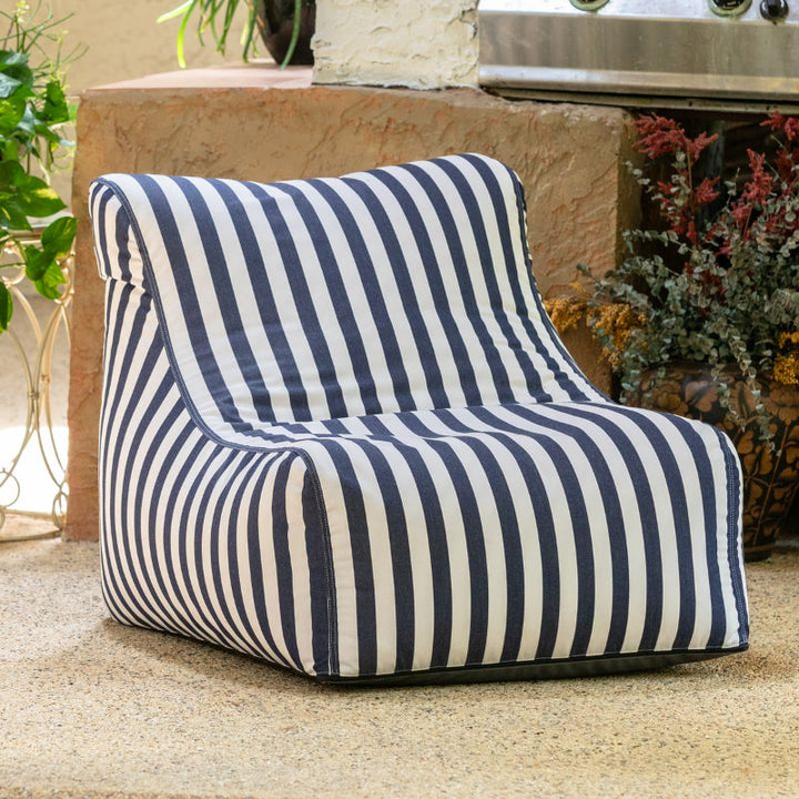 Jaxx Ponce Outdoor Bean Bag Chair in Navy Stripes tucked into a planted patio corner, a nautical striped outdoor bean bag chair