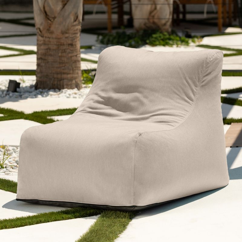 Jaxx Ponce Outdoor Bean Bag Chair in Sunbrella Flax in a garden courtyard, a warm neutral fade-resistant patio seat