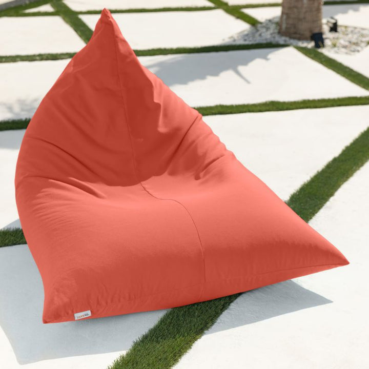 Empty Jaxx Twist Outdoor Bean Bag Chair in Flamingo on a modern turf-lined patio, showing the tall triangular back of this supportive patio bean bag