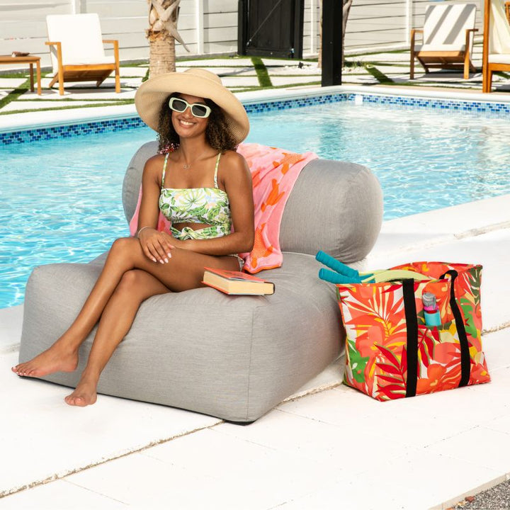 Woman relaxing on the Jaxx Tybee outdoor bean bag chair in Granite Sunbrella, a weather-resistant outdoor bean bag lounger