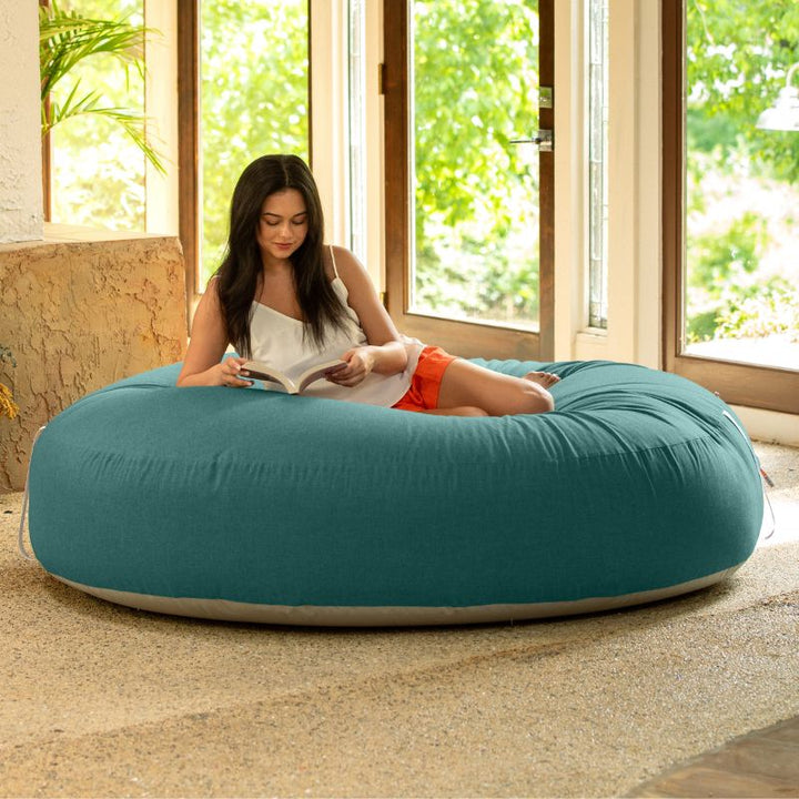 Woman reading on the Jaxx Cocoon Outdoor bean bag in Breeze fabric, oversized deep pressure seating indoors
