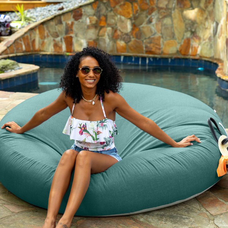 Woman sitting poolside on the Jaxx Cocoon Outdoor bean bag in Breeze fabric, weatherproof outdoor seating
