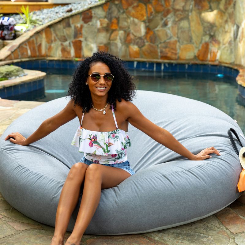 Woman sitting poolside on the Jaxx Cocoon Outdoor bean bag in Granite fabric, weatherproof outdoor seating