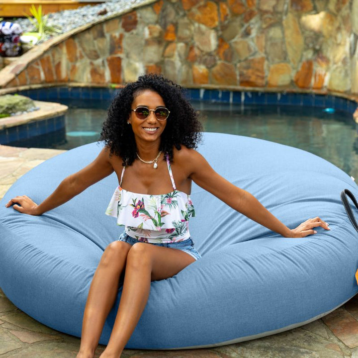 Woman sitting poolside on the Jaxx Cocoon Outdoor bean bag in Ocean Blue fabric, weatherproof outdoor seating
