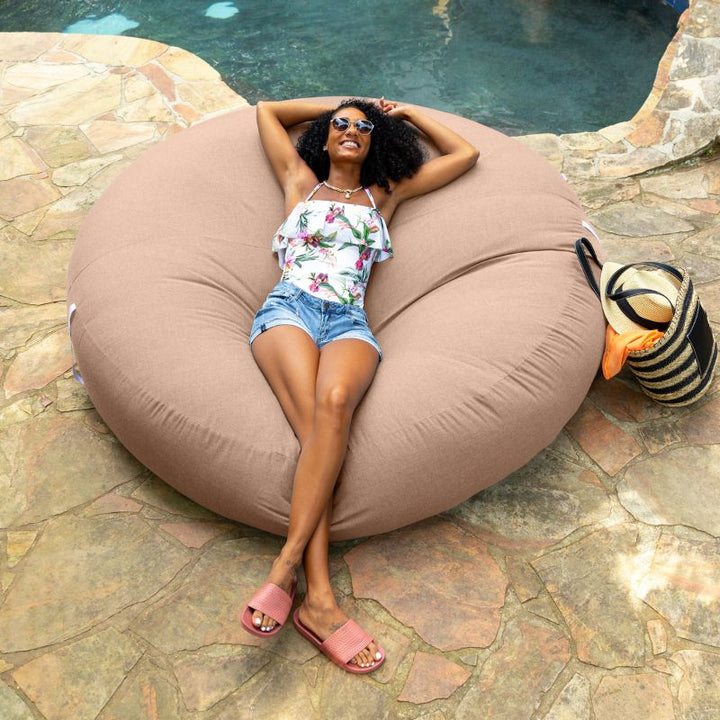 Woman relaxing poolside on the Jaxx Cocoon Outdoor bean bag in Petal fabric, weatherproof outdoor seating