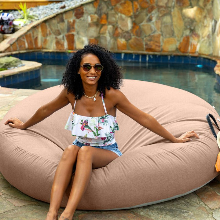 Woman sitting poolside on the Jaxx Cocoon Outdoor bean bag in Petal fabric, weatherproof outdoor seating