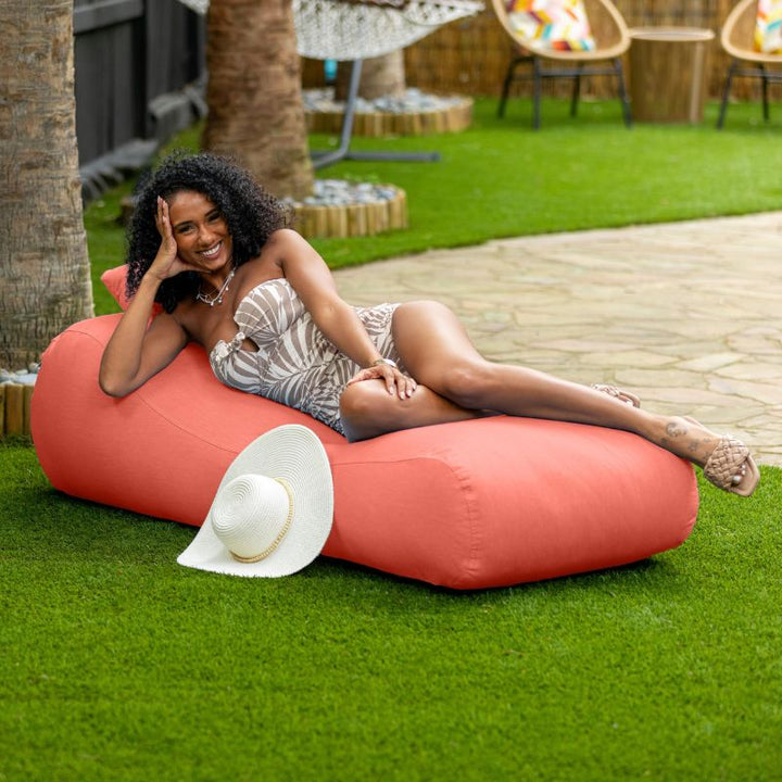 Jaxx Arlo outdoor bean bag lounger in flamingo Sunbrella fabric styled on a backyard lawn